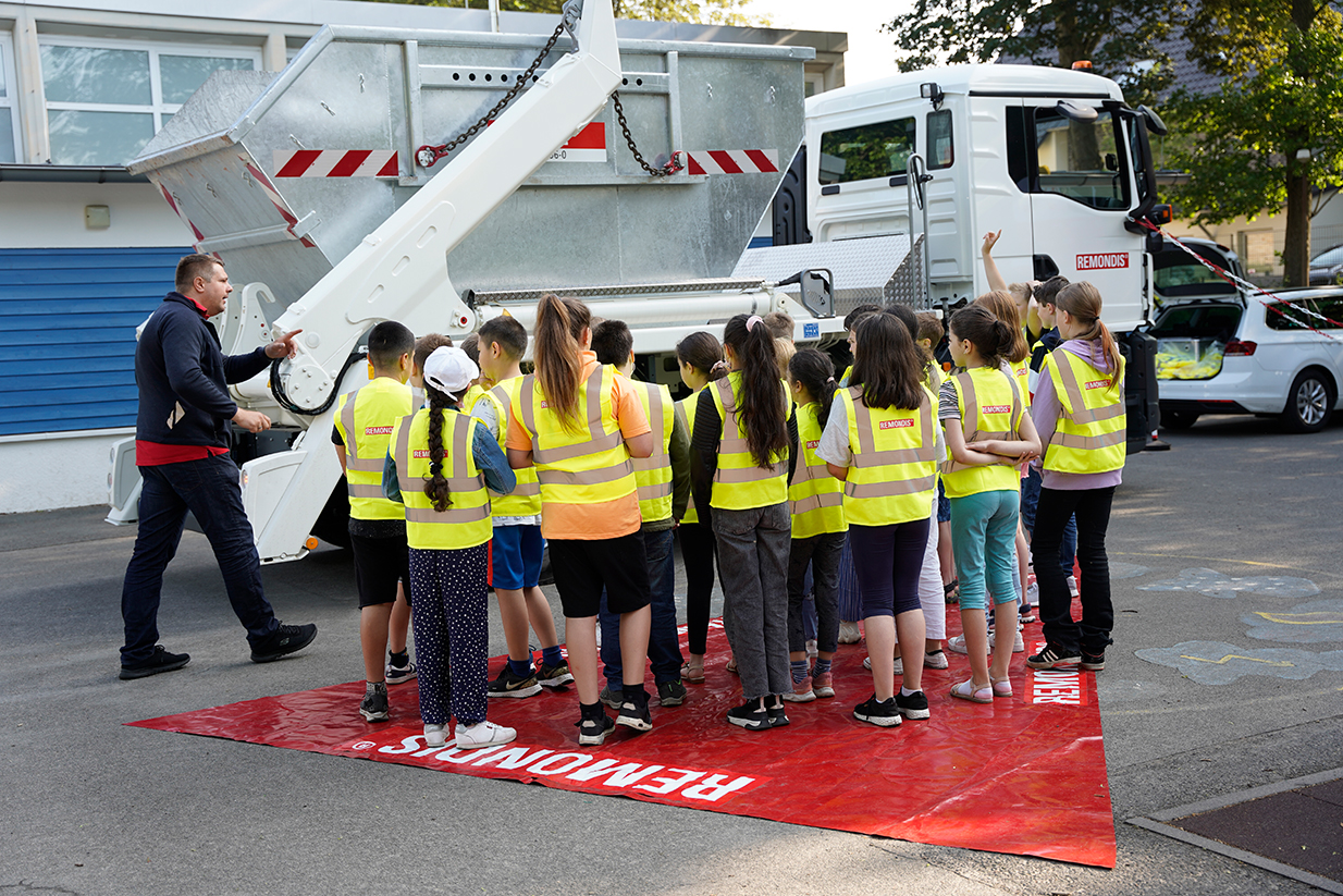 Schülerinnen und Schüler stehen alle auf dem markierten Toten Winkel. Paul Fikus erklärt ihnen die Gefahren im Straßenverkehr